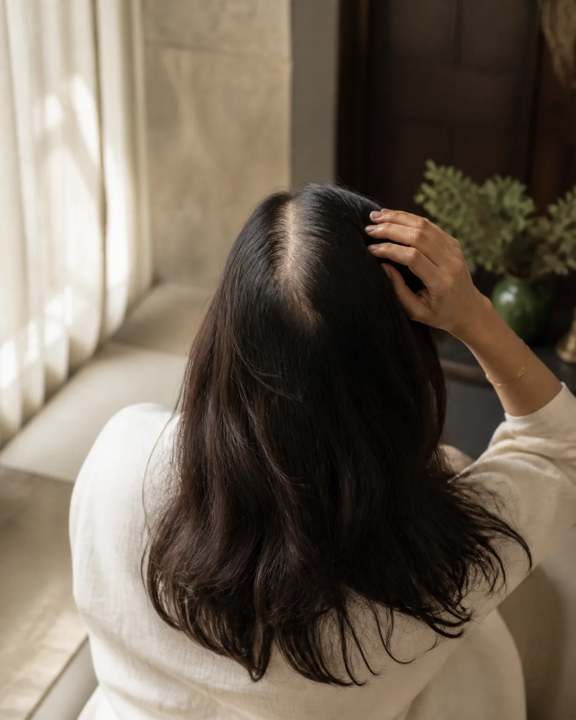 A woman looking at her hair at home